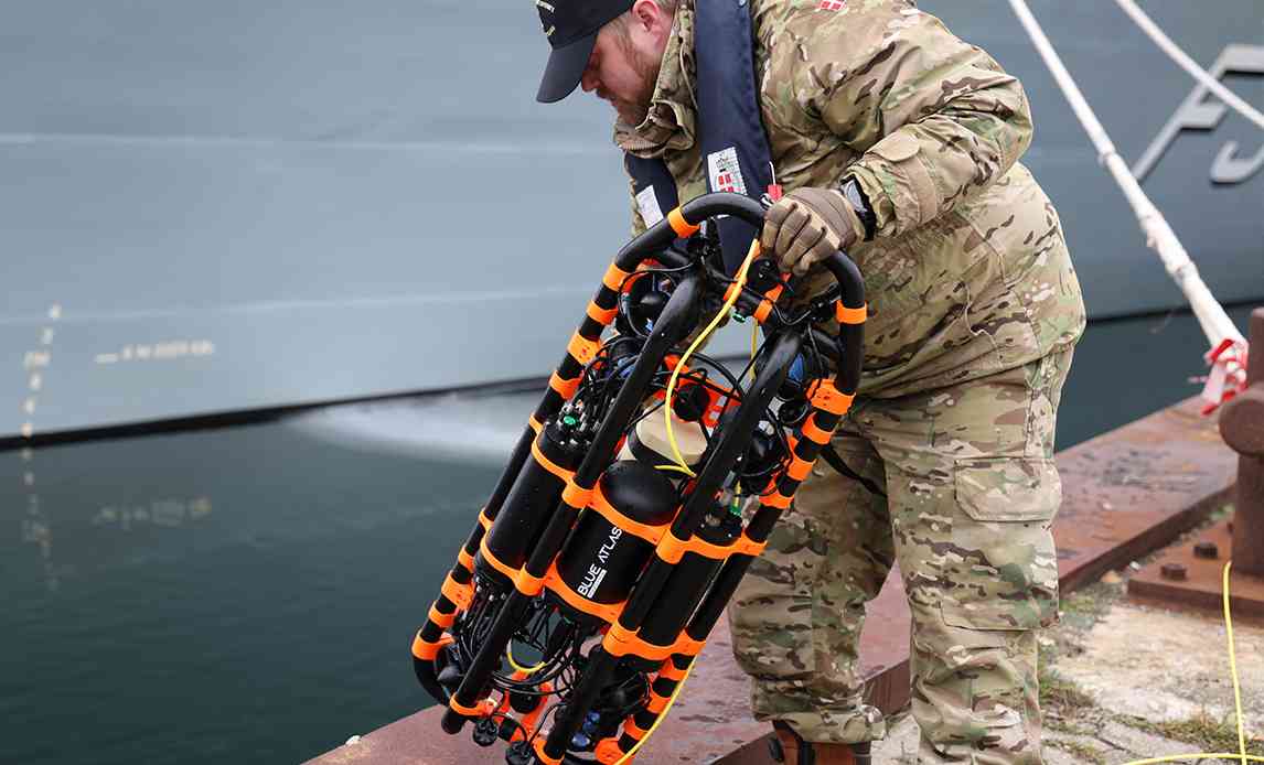 Frivillig fra Marinehjemmeværnet løfter ny drone op fra vandet.