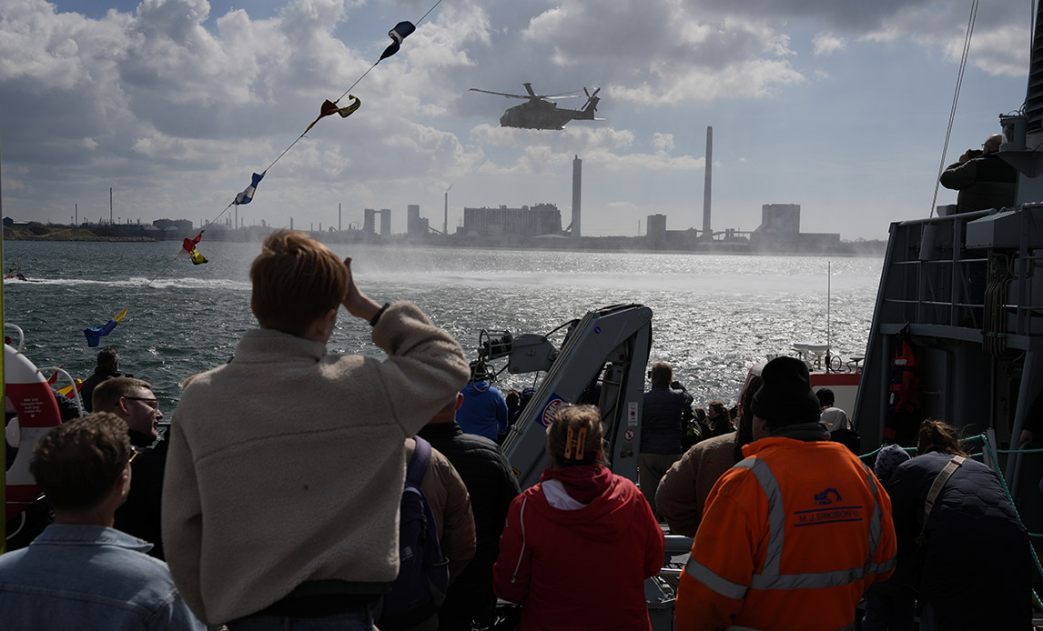Redningshelikopteren fra Flyvevåbnets Eskadrille 722 brøler ind over havnebassinet og hænger i lang tid ganske tæt på havnekanten