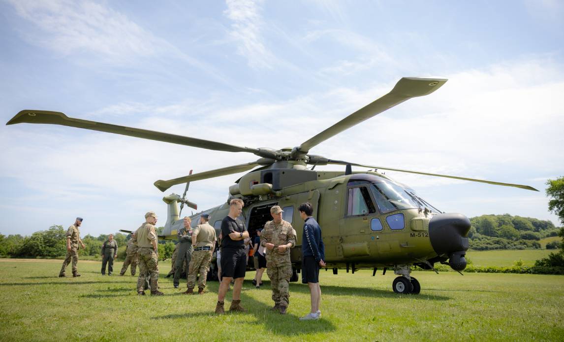 Besøgende til Soldat for en dag taler med en frivillig foran helikopter.