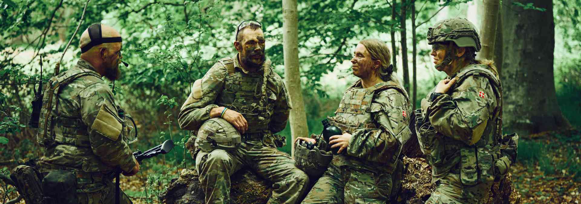 Fire hjemmeværnssoldater på øvelse står og taler sammen ude i skoven